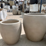 Fiber Pot Aura Beige Lifetime Warranty in UAE. Beige cylindrical concrete pots on a concrete surface with a blurred background