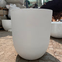 White Arco Fiber Pot with Matte Finish and Lifetime Warranty, UAE. Close-up of a white ceramic vase against a textured stone wall.