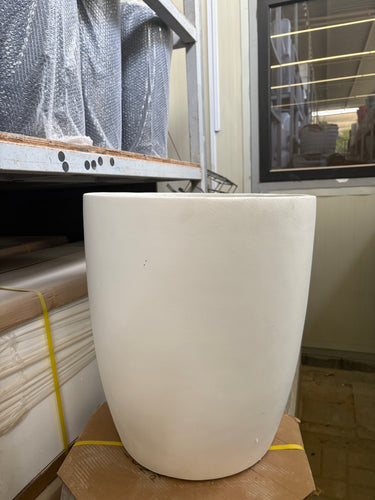 White Arco Fiber Pot with Matte Finish and Lifetime Warranty, UAE. White cylindrical object on a construction site with tools and materials in the background